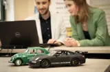 Porsche miniatuur auto met mensen op achtergrond